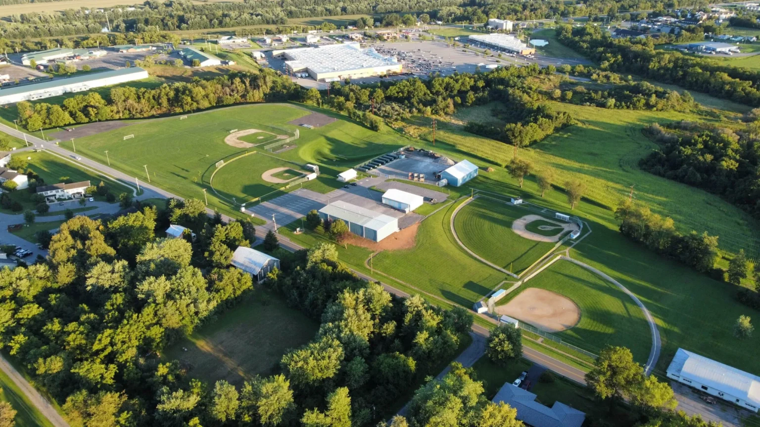 An aerial view of a large green athletic complex in Kelly Township, featuring multiple baseball diamonds, a track, and surrounding suburban roads and buildings.