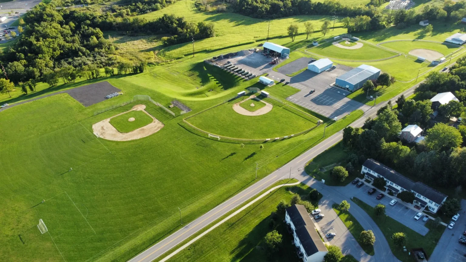 An aerial view of a large green athletic complex in Kelly Township, featuring multiple baseball diamonds, a track, and surrounding suburban roads and buildings.
